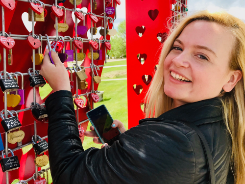 A woman places a love lock on a love lock sculpture