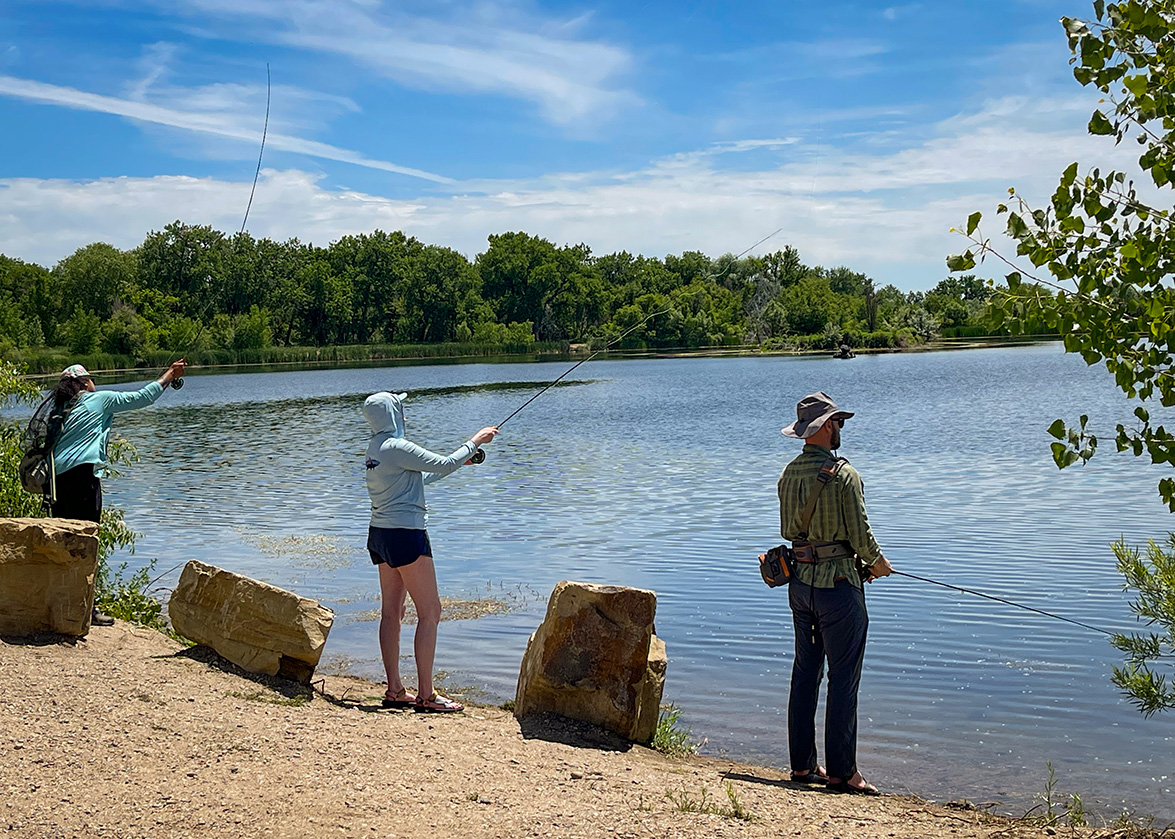 People fishing along the shore of the ponds at River's Edge Natural Area.