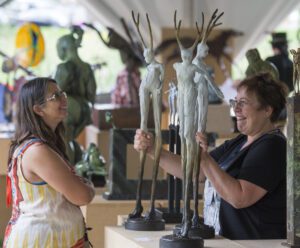 An artist shows her sculptures to an attendee at Sculpture in the Park.