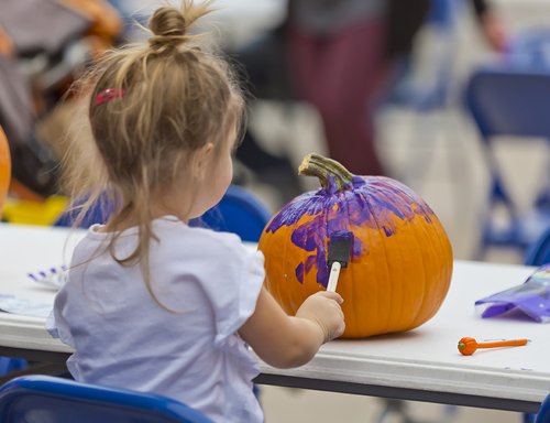 A child paints a pumkin at a table during the Loveland Pumpkin Festival