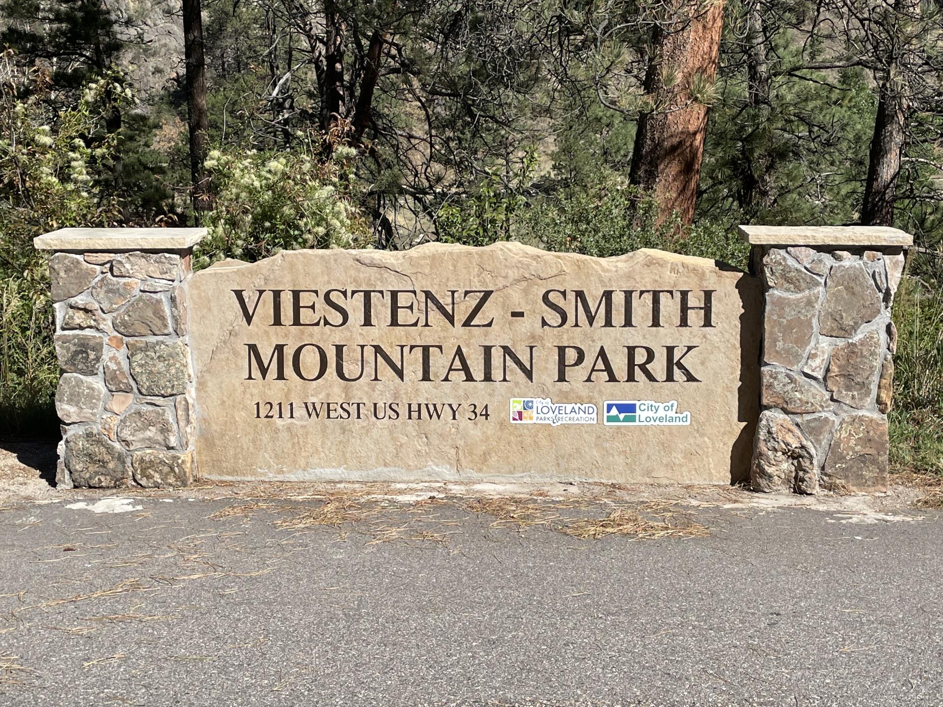 A limestone sign with the words Viestenz-Smith Mountain Park on a sunny day in Loveland, Colorado.