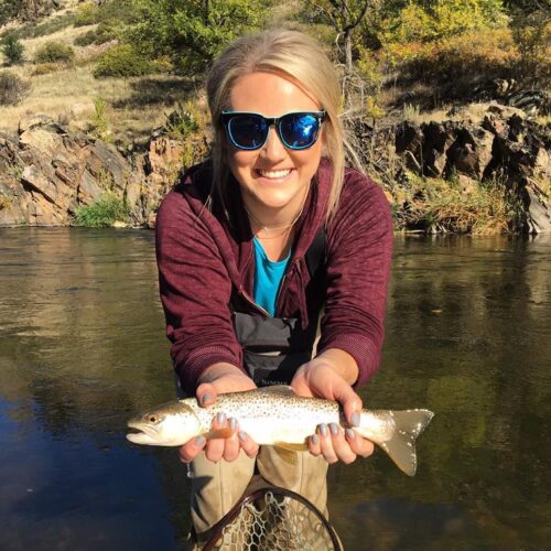 A woman holds a trout in the Big Thompson River.