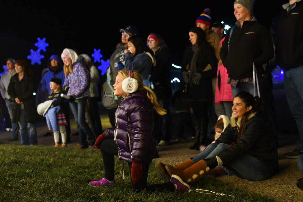 A girl kneels on the grass as she watches a live performance at Winter Wonderlights Live.