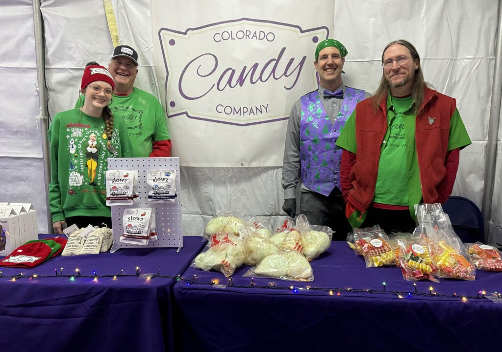 Colorado Candy Company workers pose for a picture in their booth at Winter Wonderlights