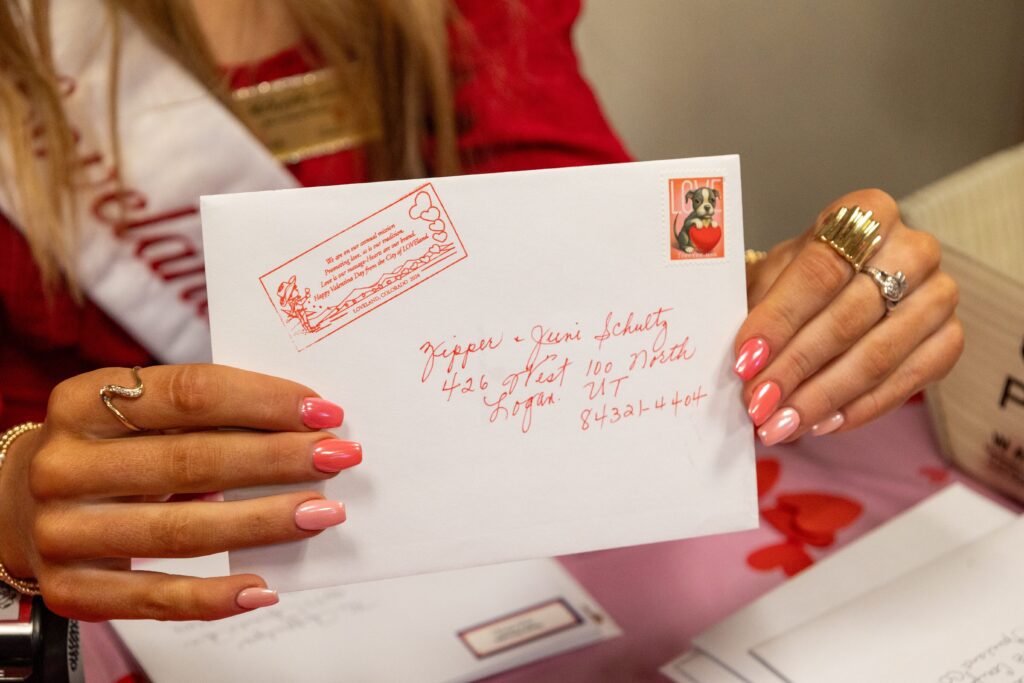 A volunteer holds up a freshly stamped Valentine at the 2024 Loveland Valentine Remailing Program stamping event.