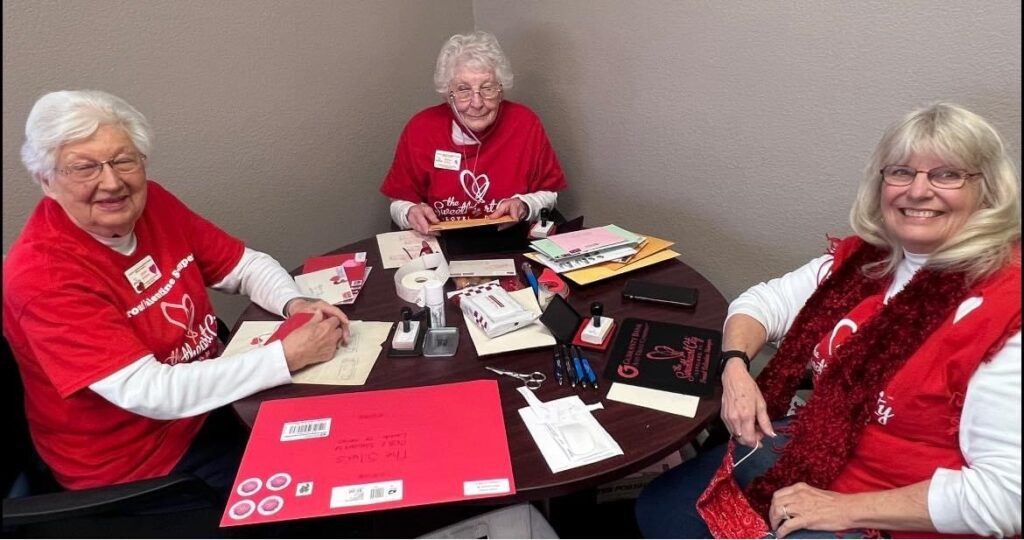 Jeanne Perrine and two other volunteers process "Chunky Monkey" valentines at a table in the Loveland Chamber of Commerce.