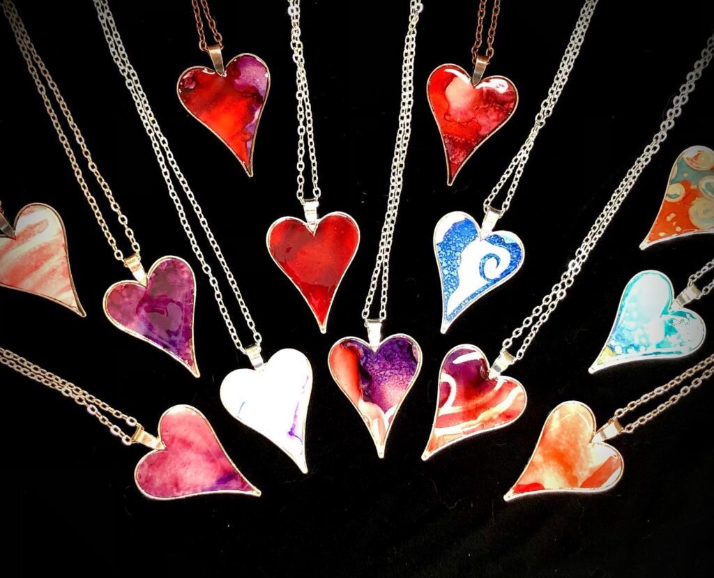 Christine James' Alchol Ink Heart necklaces on display over a black felt background.