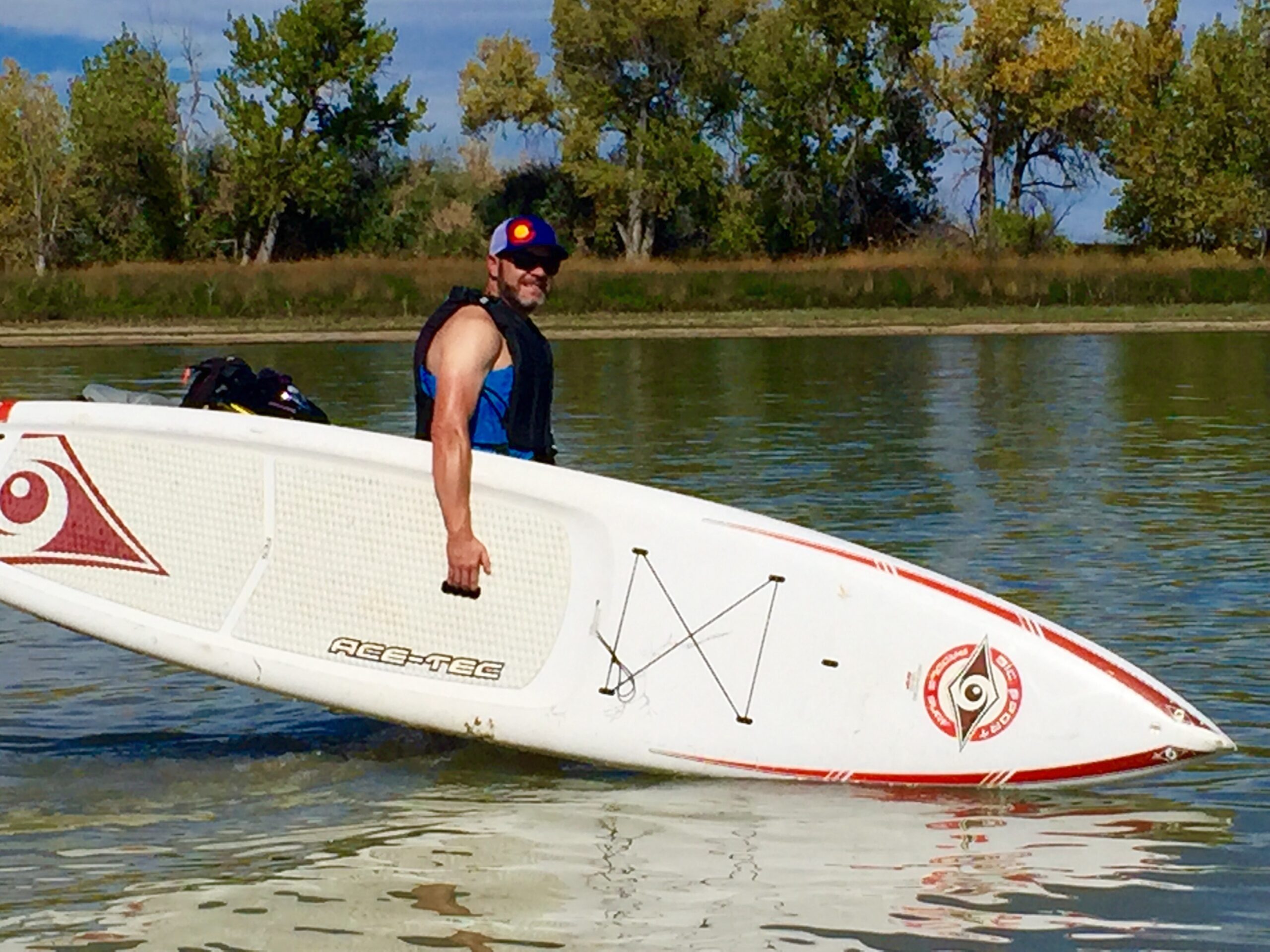 A man holds a stand up paddleboard as he enters the water at Boyd Lake State Park in Loveland, Colorado