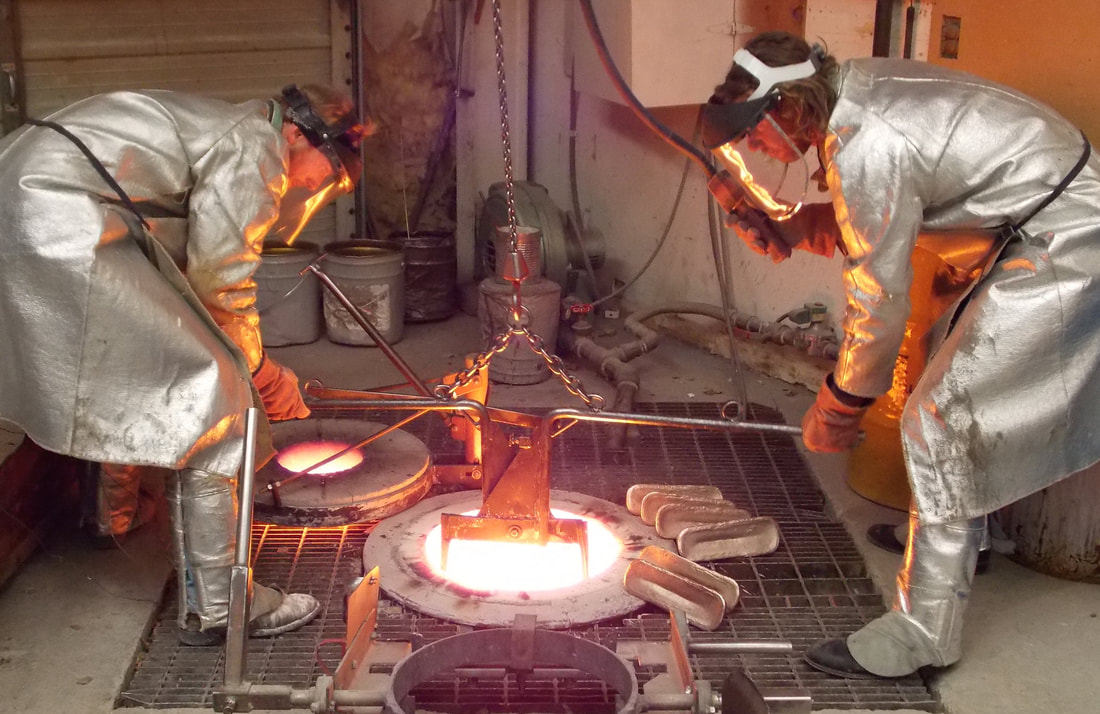 Two workers pour molten metal into a sculpture mold at Bronze Services.