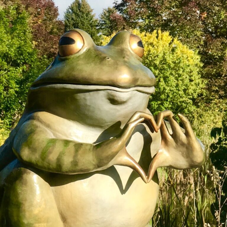 A frog sculpture holding it's hands in the shape of a heart at Benson Sculpture Garden in Loveland, Colorado.