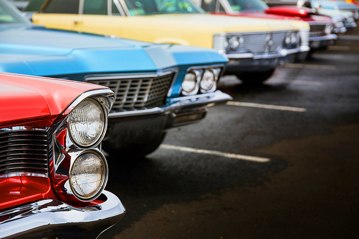 Classic cars sit in line at a car show.